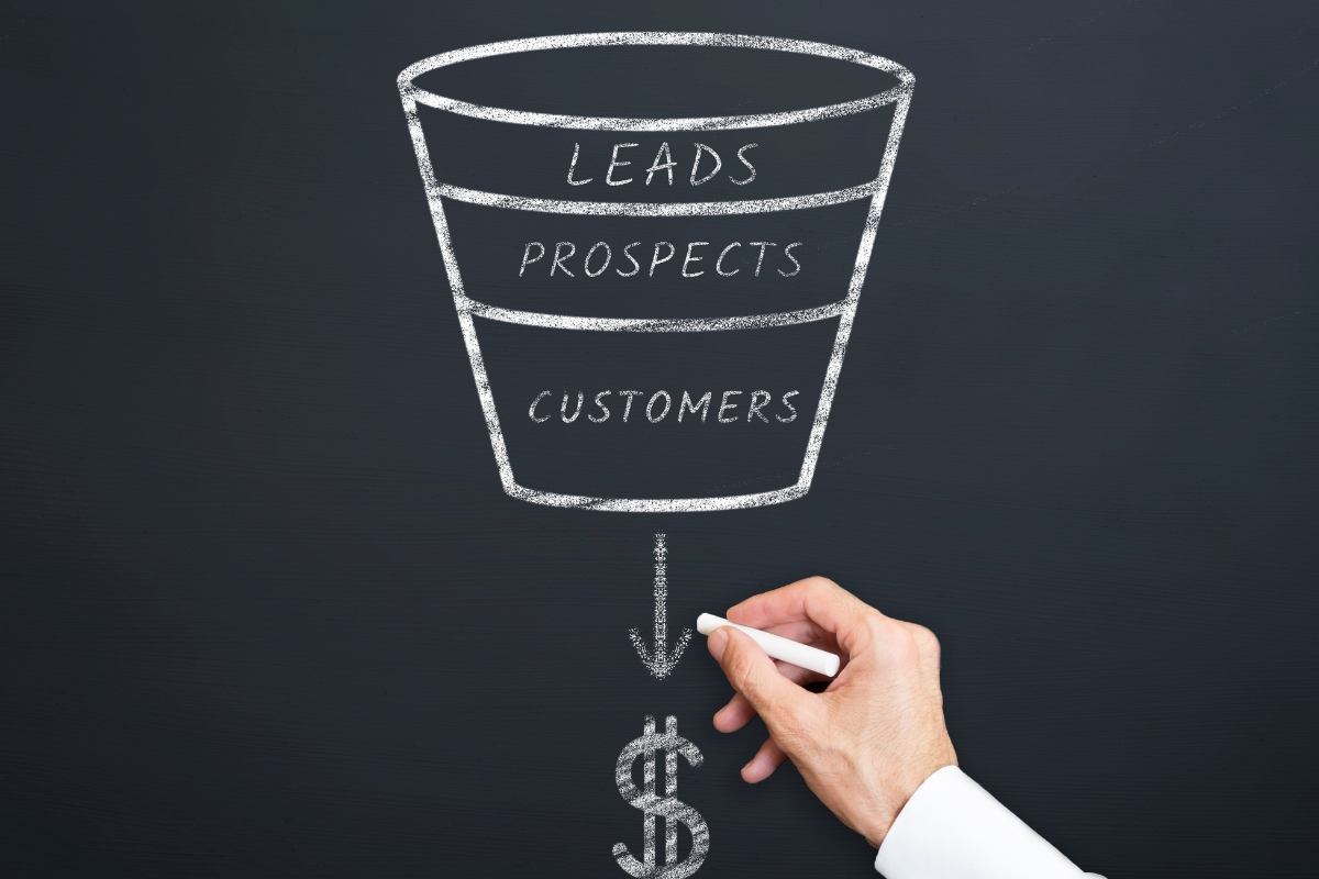 A hand drawing a sales funnel with leads, prospects, and customers.