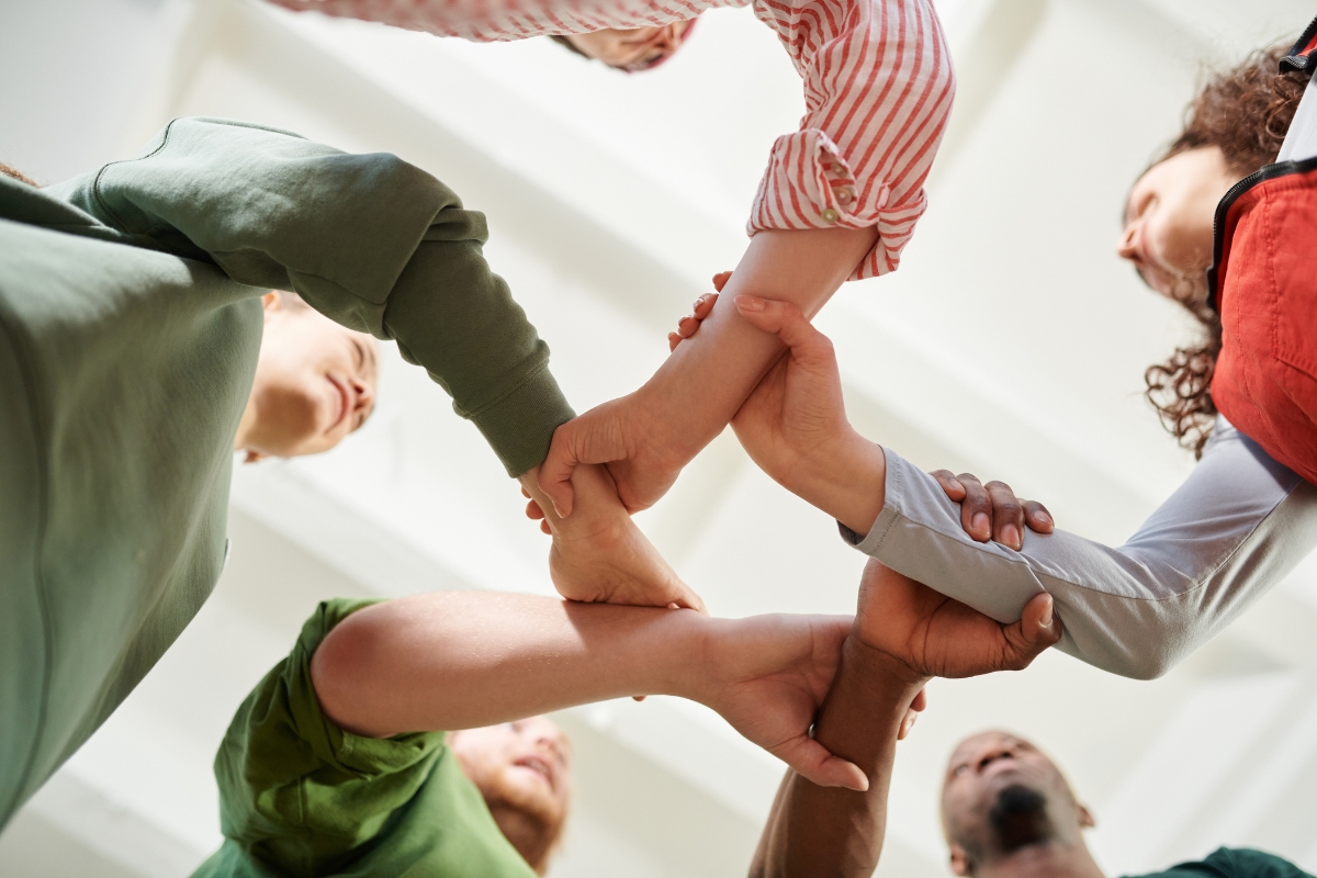 Group of people joining hands in a circle from a low angle perspective, symbolizing word of mouth marketing.