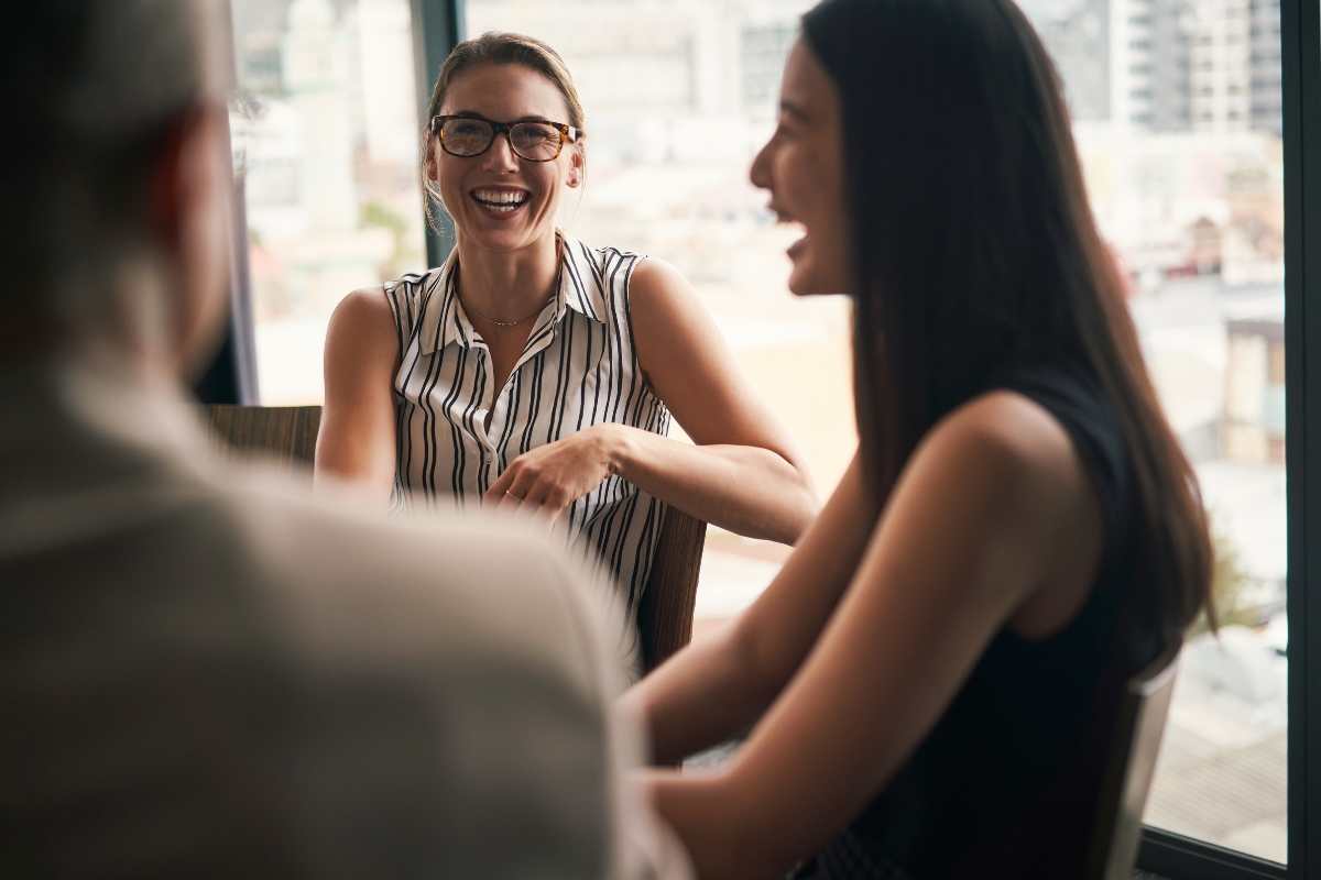 A group of women laughing, spreading joy through word of mouth marketing.