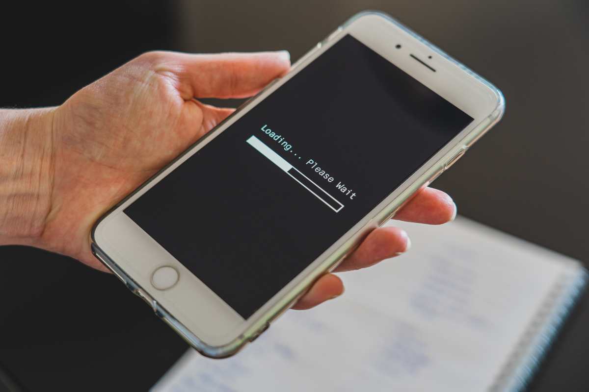 A person holding a phone that says "loading, please wait."