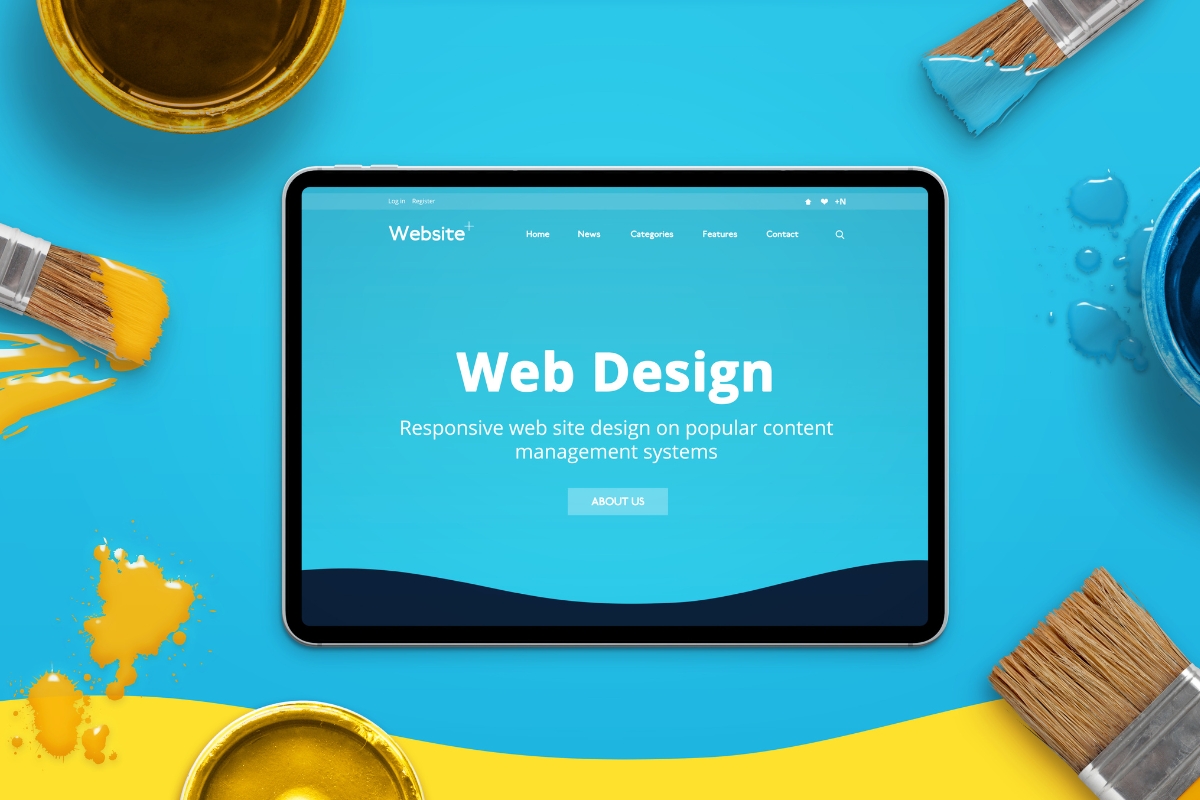 Tablet displaying an Elementor web design page in WordPress, surrounded by paint brushes and paint pots on a blue background.