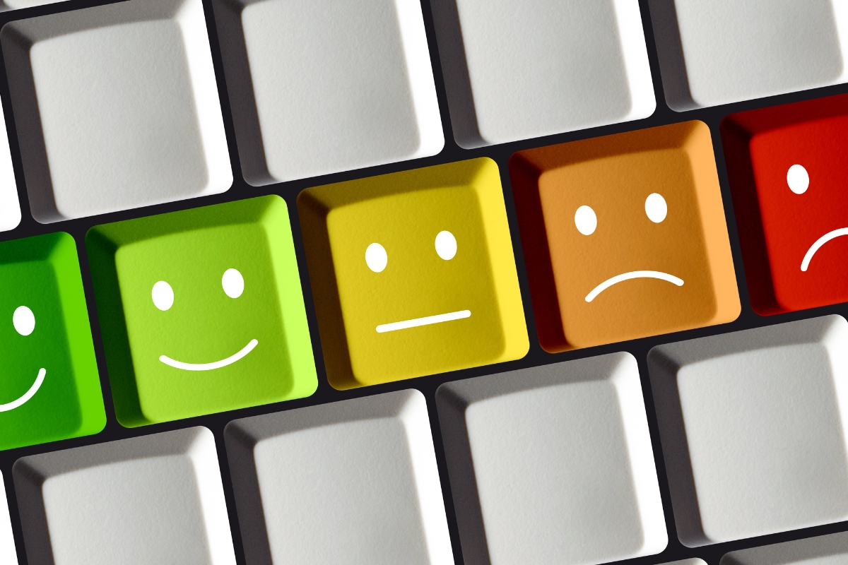 Keyboard keys in a row with emoticon faces displaying different emotions for Google reviews; two happy faces, one neutral face, and one sad face on colorful backgrounds.