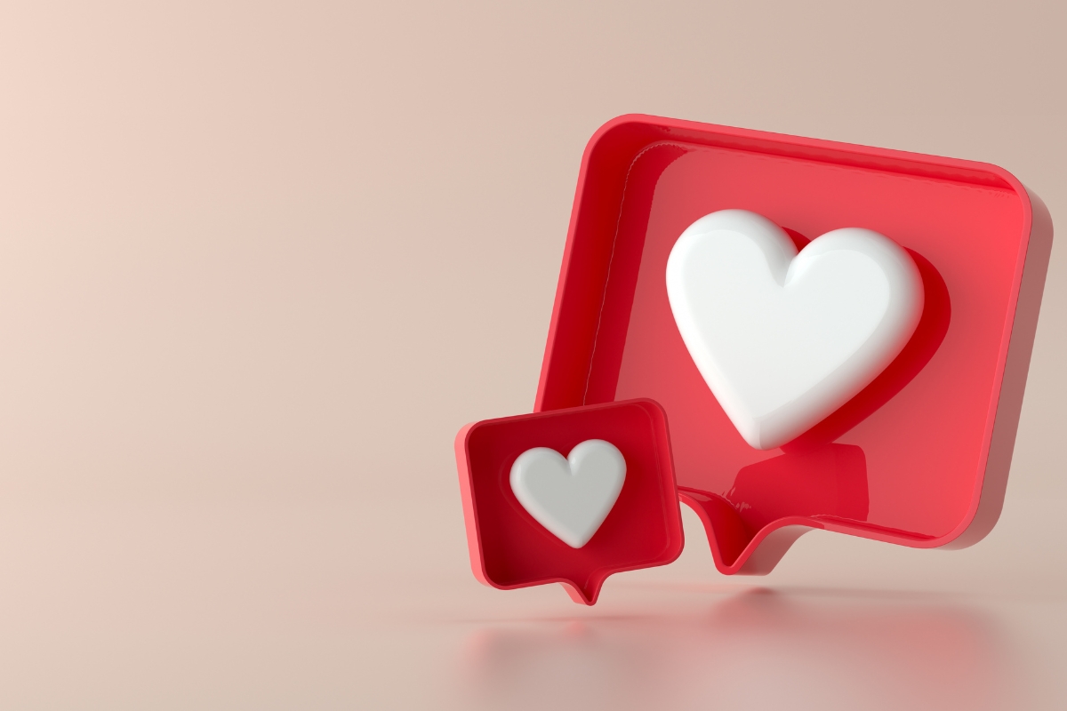 Two nested heart-shaped speech bubbles in red and white, on a soft pink background, symbolizing loving communication on how to improve your Facebook business page.