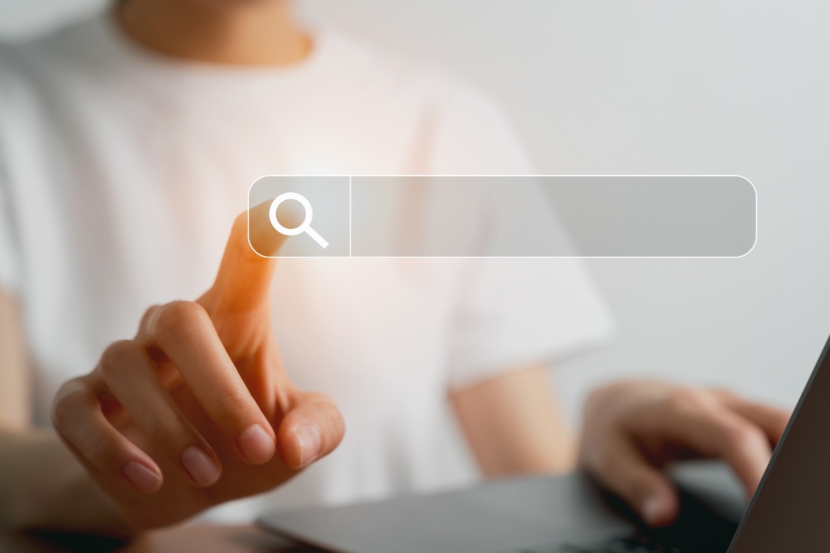 Person using a laptop and clicking on a digital search bar projected in front of them to learn how to search on a website.