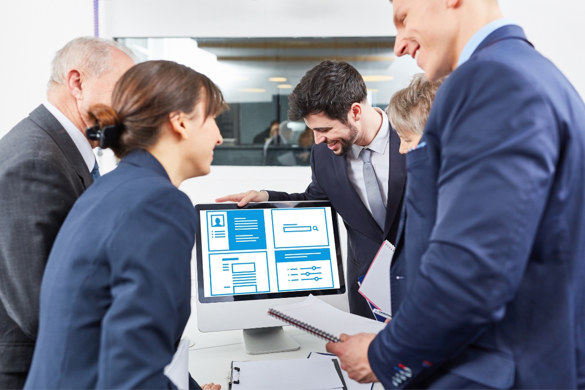 Business colleagues discussing local business citations data on a computer screen in a modern office setting.