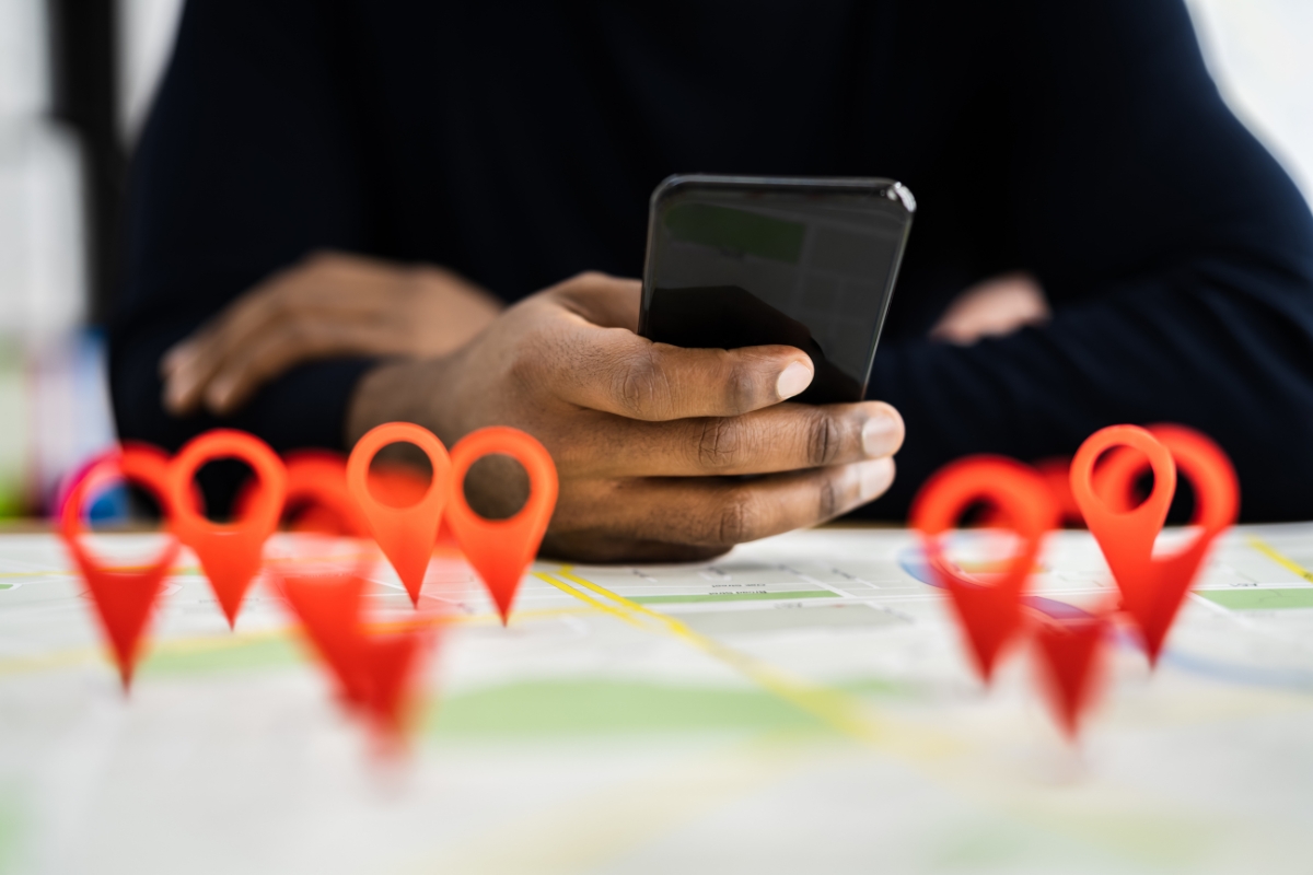 Person holding a smartphone over a map with multiple red location pins indicating local business citations.