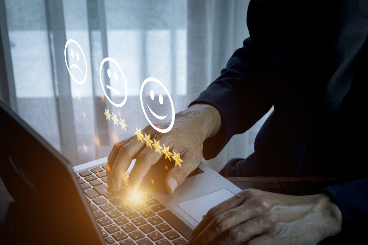 Professional in a suit using a laptop with floating digital icons showing smiley faces and star ratings, indicating positive online reputation and customer satisfaction.