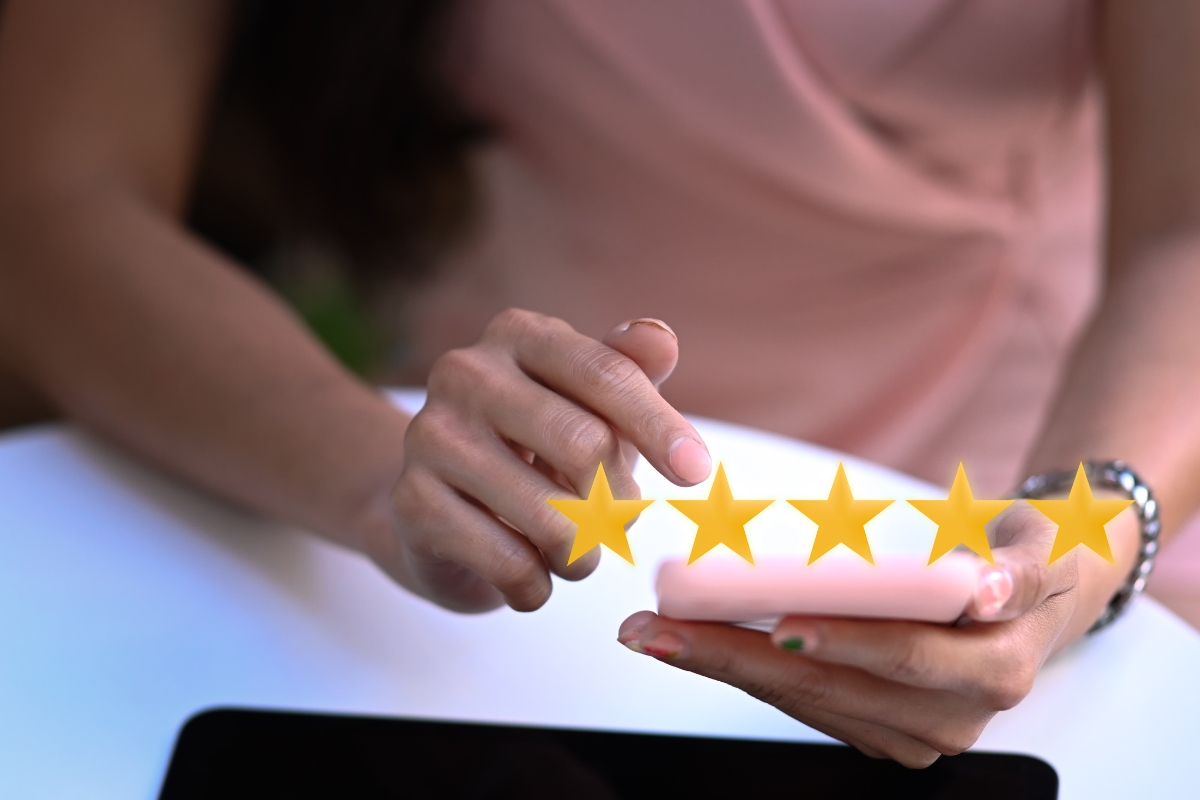 A person's hands holding a smartphone displaying five gold stars on the screen, symbolizing a positive online reputation.