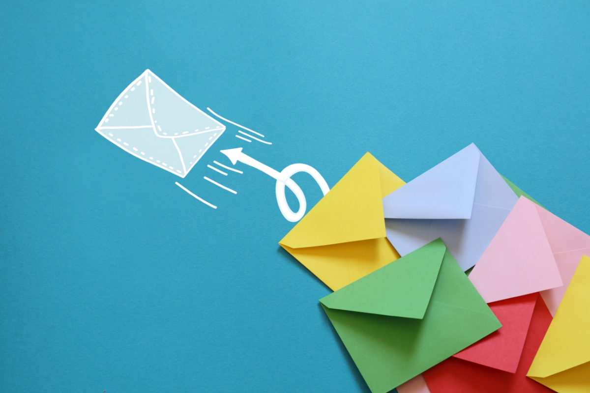 Colorful envelopes are spread out on a blue background with a drawing of a white envelope and an arrow pointing upward, symbolizing the rise of email marketing for plumbers.