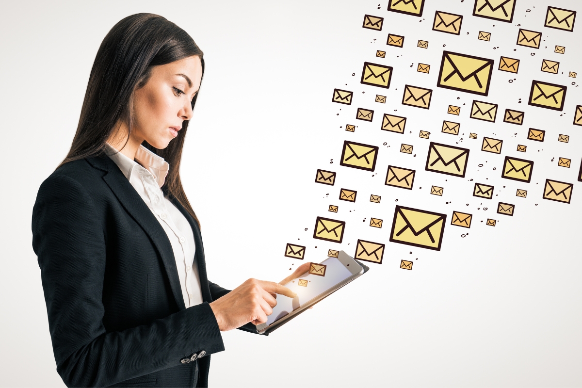 A woman in a suit operates a tablet with numerous digital mail icons emanating from it, symbolizing email marketing for plumbers.