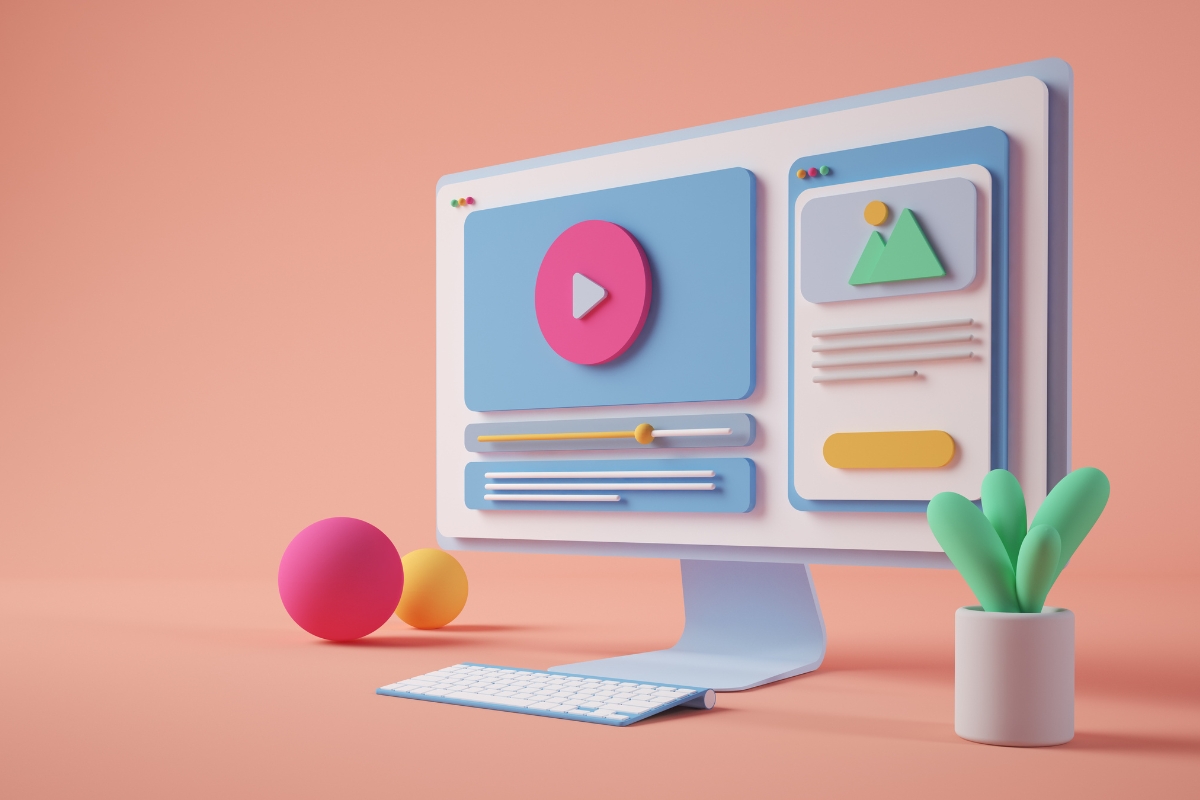 A computer monitor with colorful 3D shapes on the screen sits on a peach-colored desk. Nearby are two spherical objects and a small potted plant, subtly hinting at the seamless integration of plumbing automation in this modern workspace.