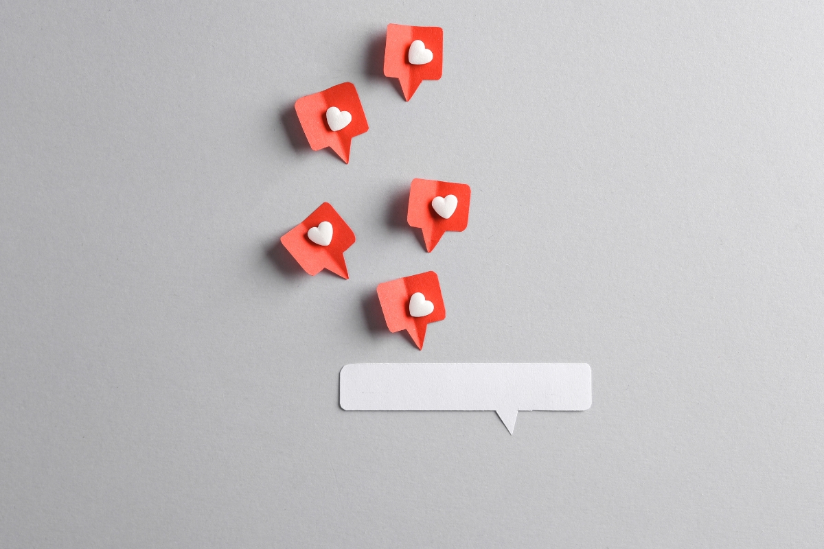 Five red speech bubble icons with white hearts inside are positioned above a blank white speech bubble on a grey background, representing the power of social media marketing for local businesses.