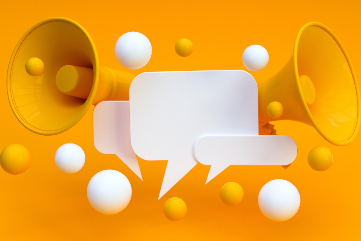 Two yellow megaphones face outward against an orange background, symbolizing a dynamic social media marketing plan. White and yellow speech bubbles and spheres surround the megaphones, emphasizing communication and engagement.