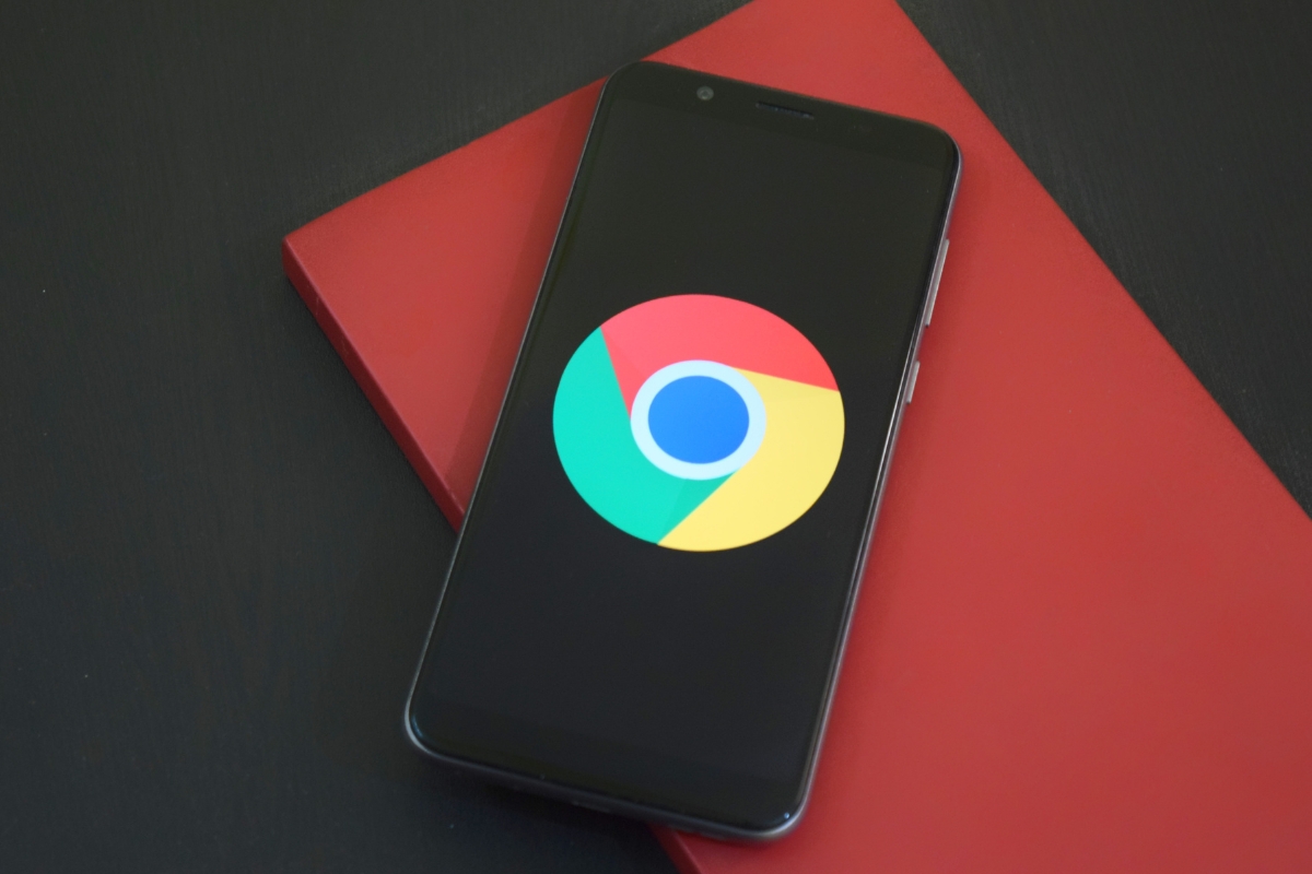 A smartphone displaying the Chrome browser logo on its screen is placed on a red notebook against a black background, making one ponder what is Google Workspace and how seamlessly it integrates with everyday tools.