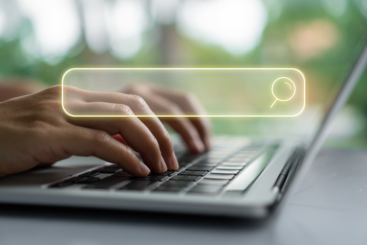 Hands typing on a laptop keyboard with a glowing search bar graphic overlayed, symbolizing internet search or online browsing, as if inquiring, "What is Ecosia search engine?