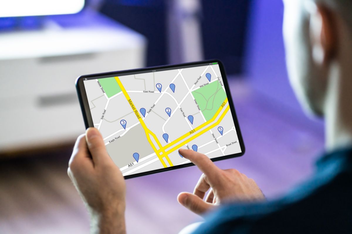 A person is using a tablet to view a digital map with several location markers, likely learning how to use geofencing marketing.