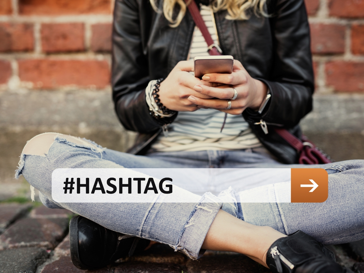 a woman sitting on the ground using a phone with #hashtag on it