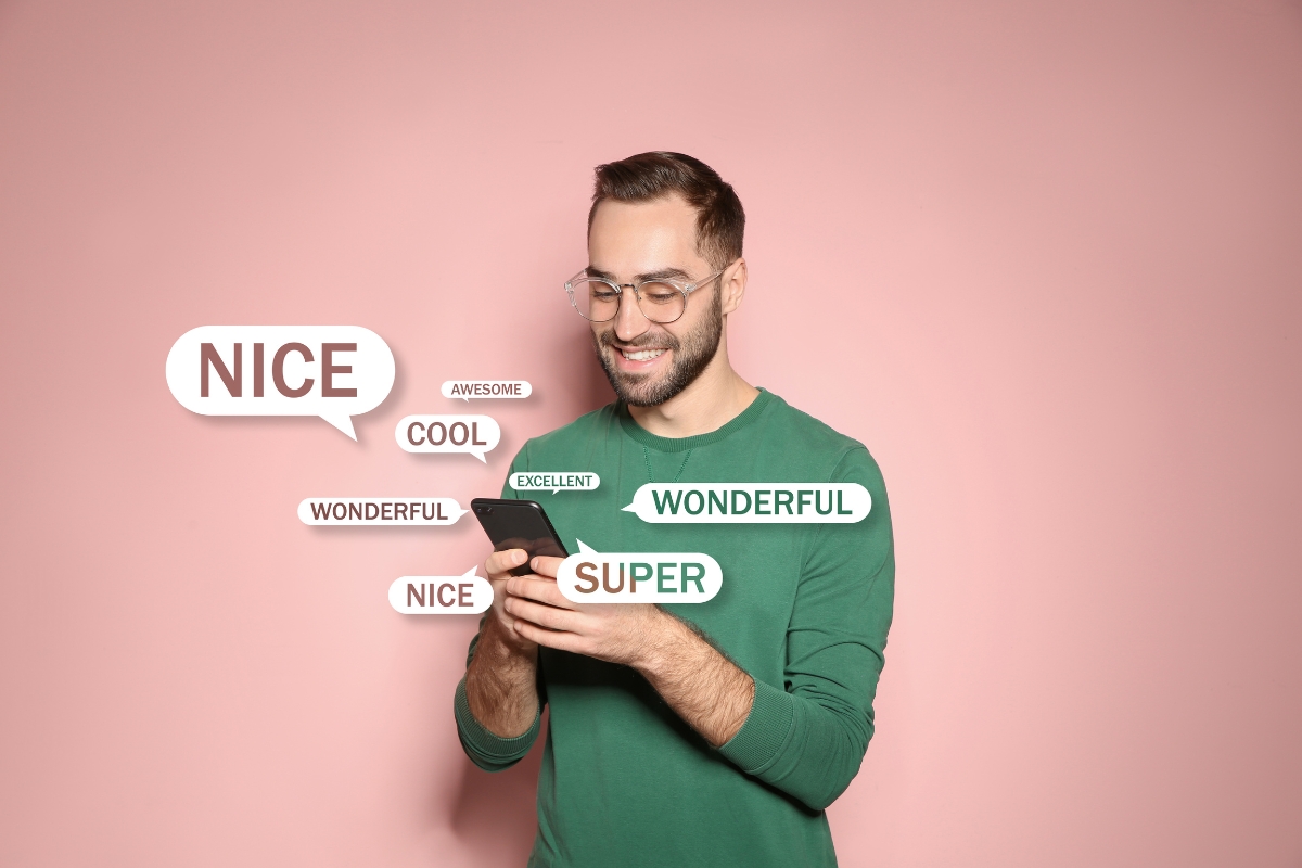 A man in a green shirt looks at his phone while text bubbles around him display words like "NICE," "COOL," "SUPER," and "WONDERFUL." The scene seems to capture his moment of inspiration on how to come up with content ideas, all set against a solid pink background.