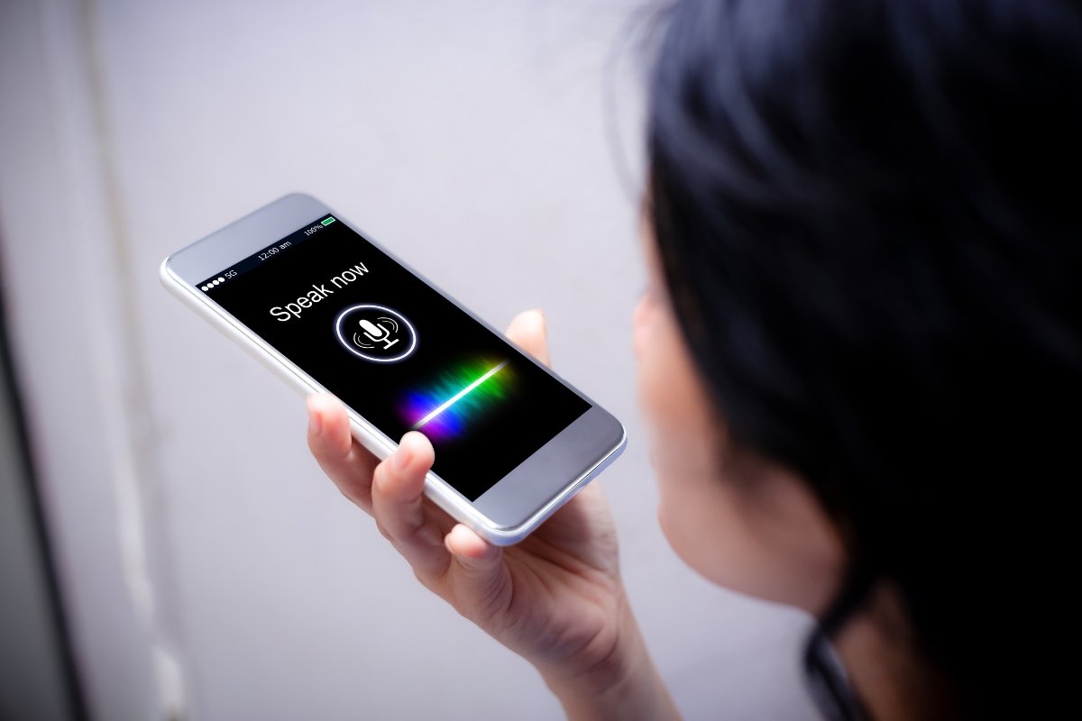 Person holding a smartphone near their mouth with the screen showing a "Speak now" voice command prompt, perfect for learning how to optimize your website for voice search.