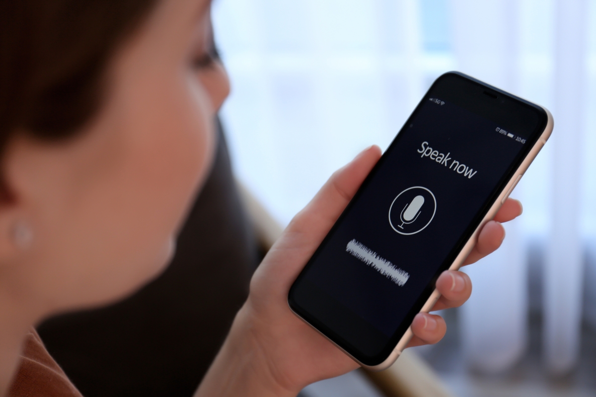 A person holds a smartphone displaying a voice input screen with the prompt "Speak now" and a microphone icon, demonstrating how to optimize your website for voice search.