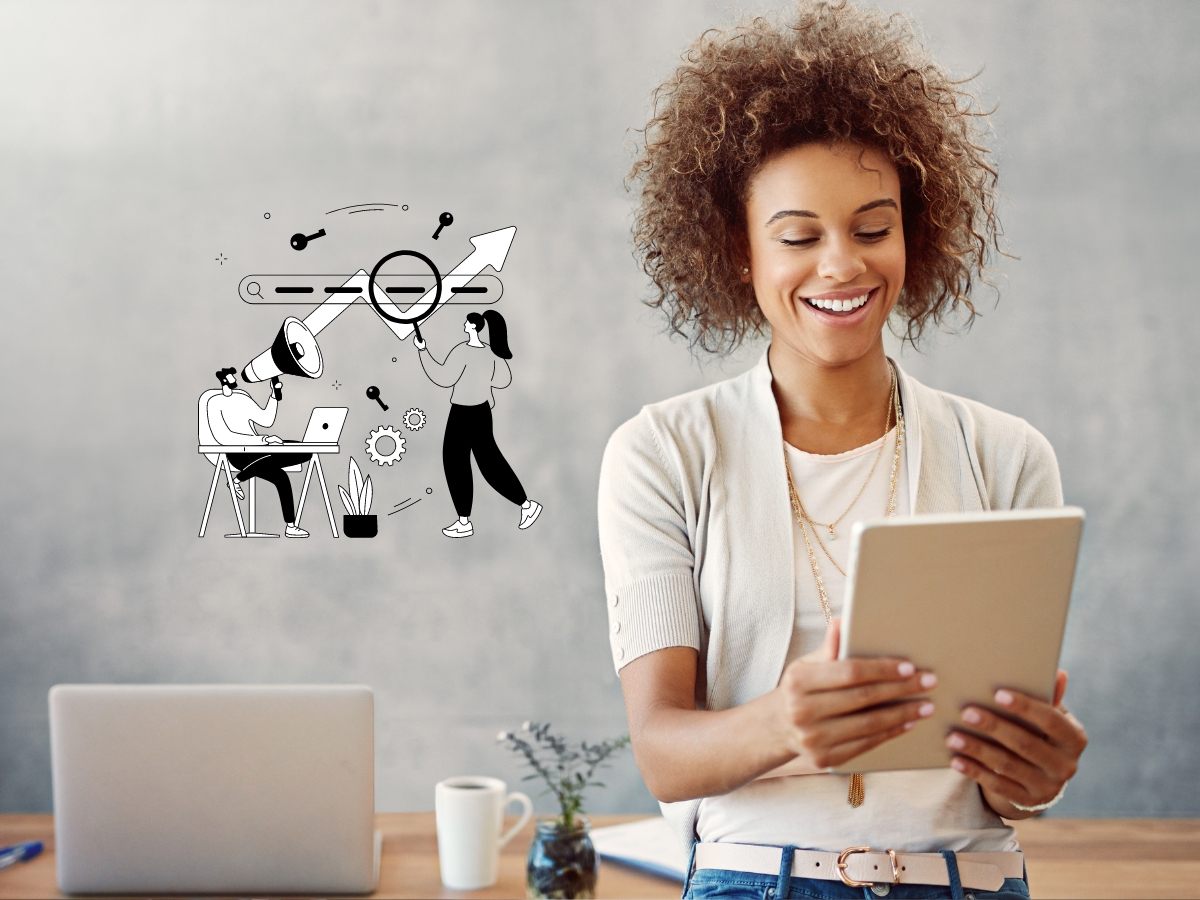 A woman smiles while looking at a tablet with a laptop and office supplies on the desk in front of her. Behind her, a small illustration depicts teamwork and innovation concepts, reflecting the dynamic spirit of a small business embracing seasonal keywords for optimal SEO.