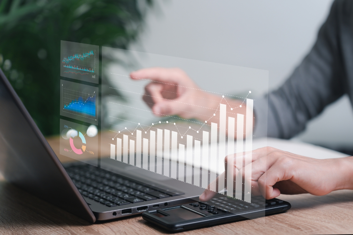 A person uses a calculator and laptop displaying financial graphs and charts in a visually transparent overlay, pondering the question: what does UTM stand for?