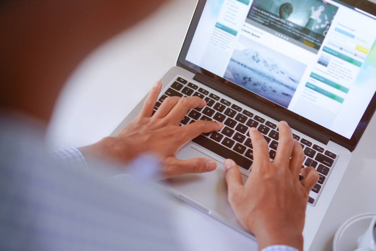 Person using a laptop with hands on the keyboard, viewing a website displaying various articles and images related to what is Guest Blogging.