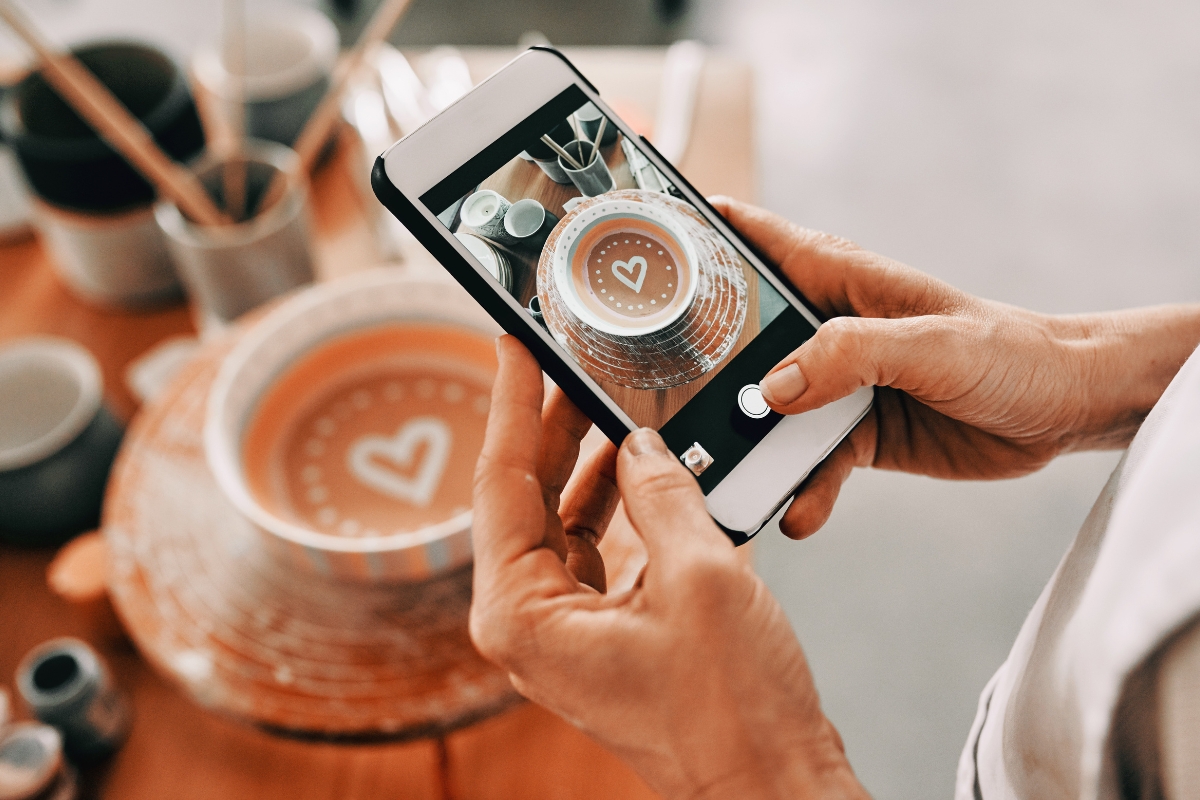 A person is taking a photo of a ceramic bowl with a heart design on it using a smartphone, showcasing how capturing and sharing unique moments highlights why social media is important.