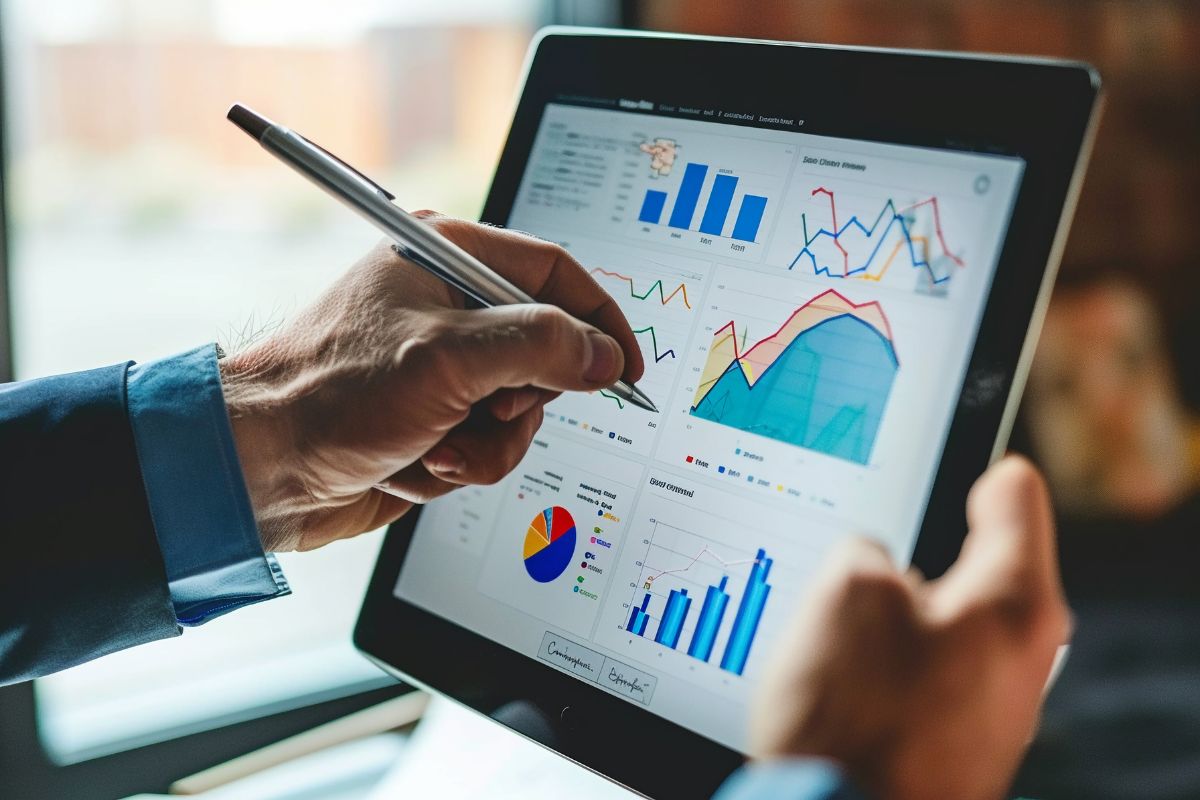 A person holds a tablet displaying various charts and graphs while pointing with a stylus, analyzing data on CRM marketing automation.