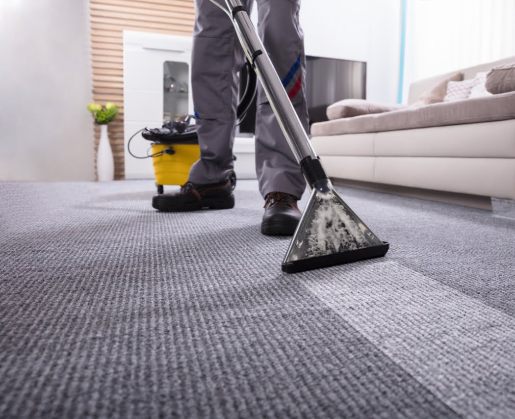 A carpet cleaner business cleans carpet he scheduled with a client using his carpet cleaner crm software.The room contains a beige sofa, a white cabinet, and a TV.