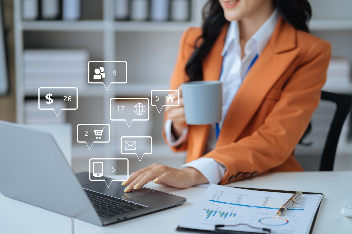 A woman in an office setting holds a mug while using a laptop. Various social media and notification icons are overlaid, indicating digital interactions, which can transform customer service. A document and pen are on the desk.