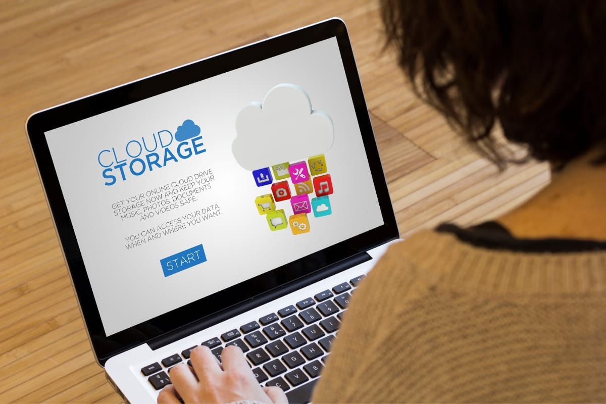 A person uses a laptop showcasing a cloud storage application, prominently featuring a start button and details about online file access through advanced cloud backup services.