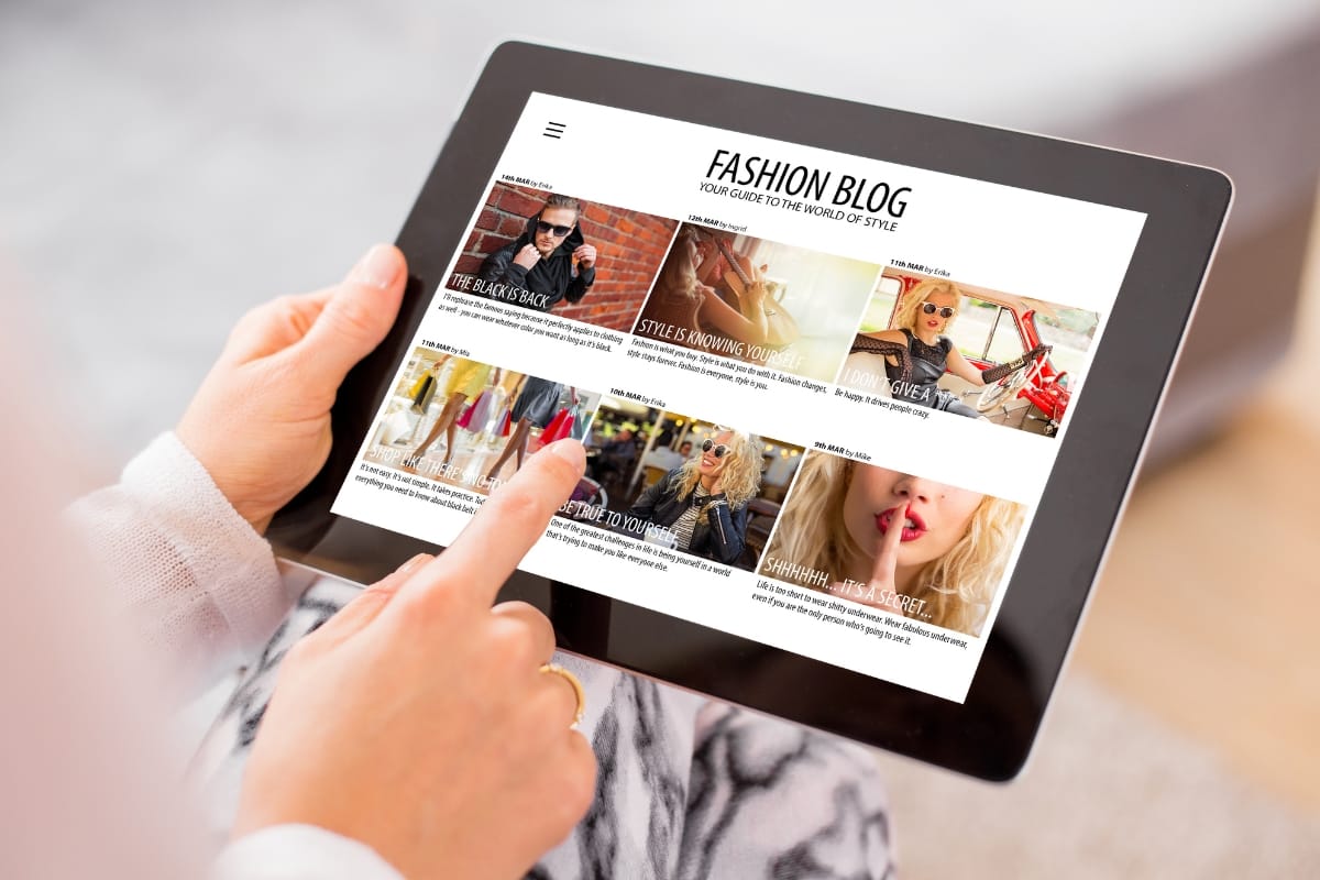 A person holds a tablet displaying a fashion blog brimming with engaging content creation, featuring photo articles on style trends and accessories.