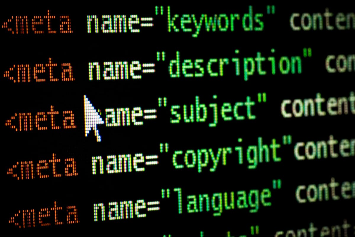 Close-up of a computer screen displaying HTML meta tag code, with terms like "keywords," "description," and "subject" highlighted in different colors. A cursor is pointing at "name," typically seen when editing WordPress posts for better SEO optimization.