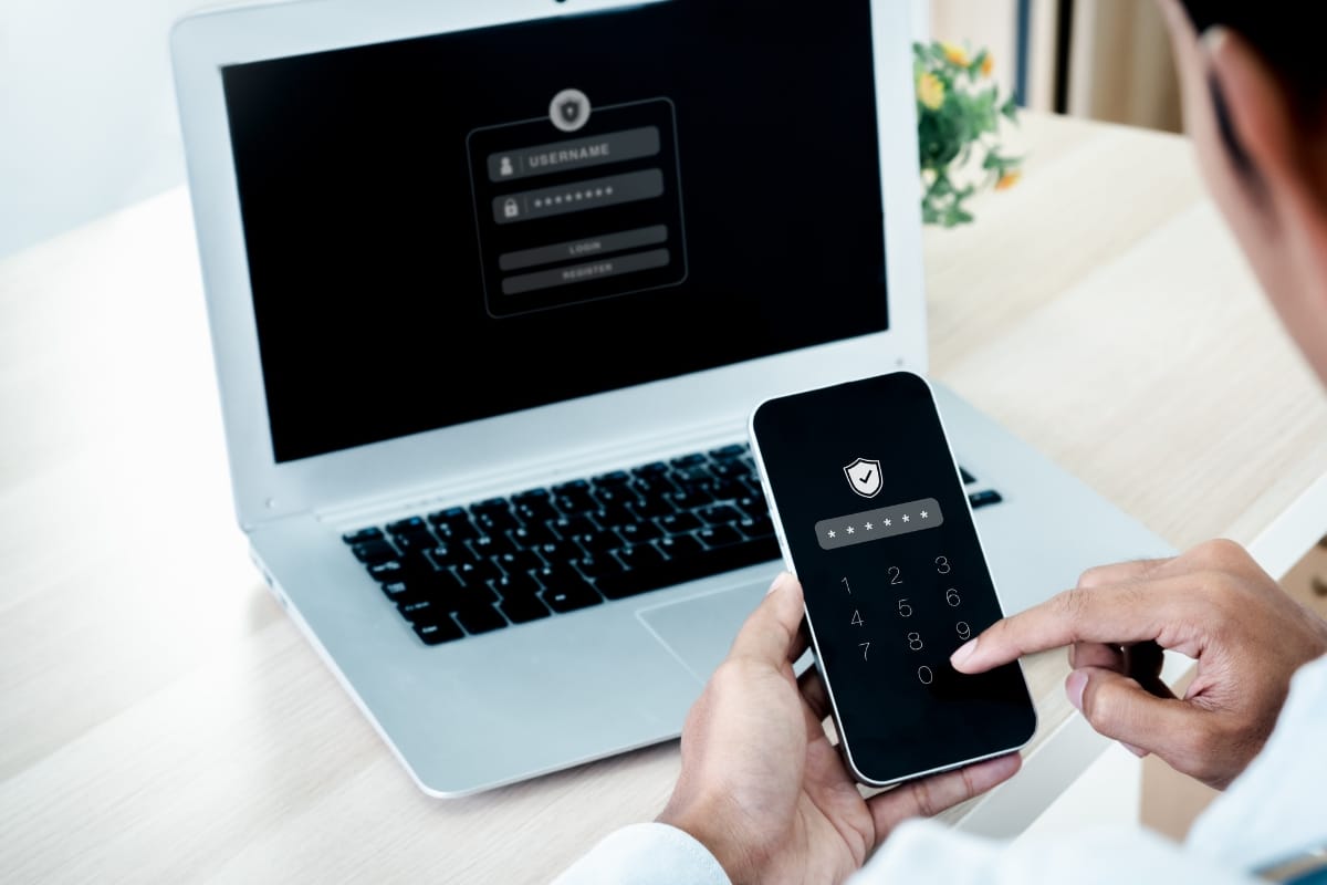 A person is using their smartphone for two-factor authentication in front of a laptop displaying a WordPress login screen, following security best practices to safeguard their account.