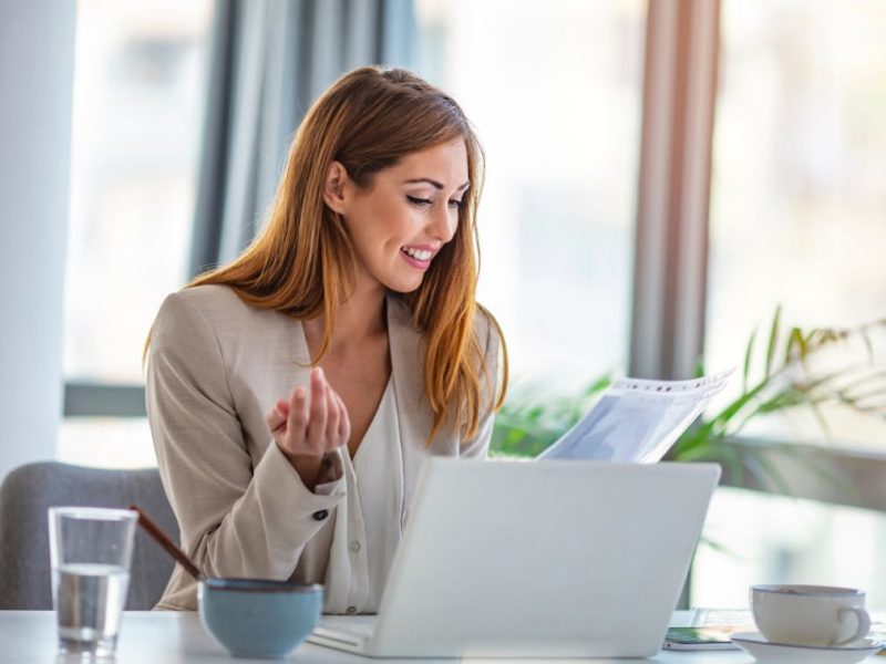 A woman is sitting at a desk with a laptop in front of her.