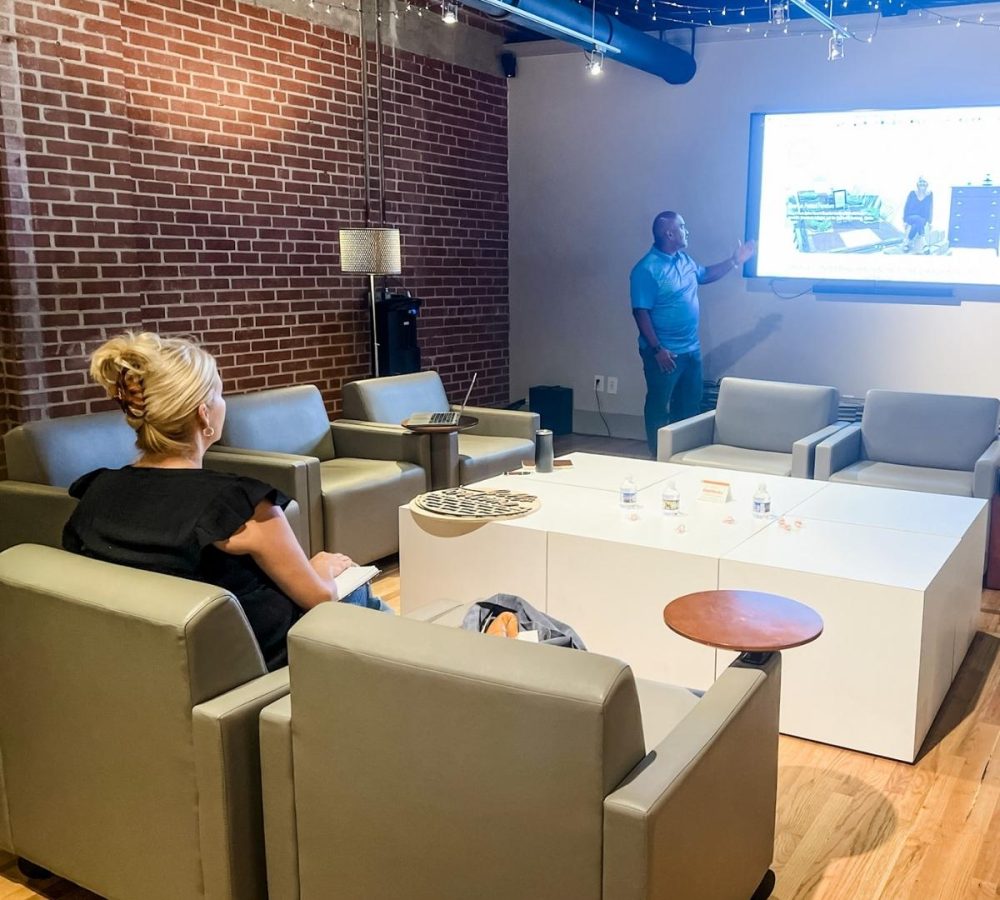 A social media marketing agency meeting with clients around a projector screen.