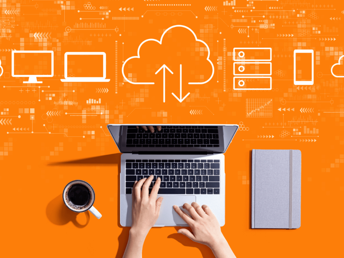 Hands typing on a laptop, with cloud icons, servers, and various device illustrations above, symbolizing cloud computing and data synchronization, on an orange background. A coffee and notebook are beside the laptop, ideal for setting up the best WordPress backup solutions.