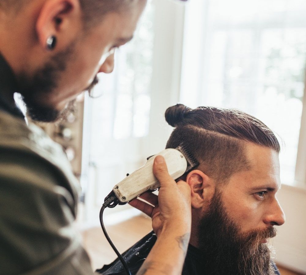 A man is getting his hair cut at a salon.