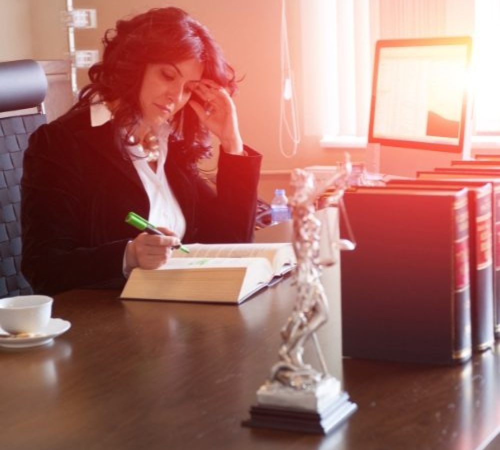 An attorney in a suit sitting at a desk with a book, able to do her work while Newman Web Solutions provides SEO for Attorneys/Lawyers.