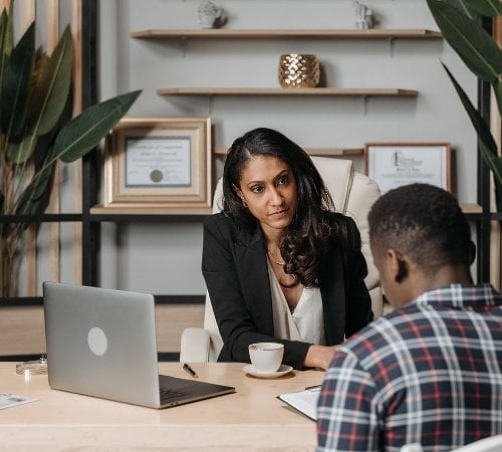 A woman is discussing attorney website design with a man at a desk in an office.